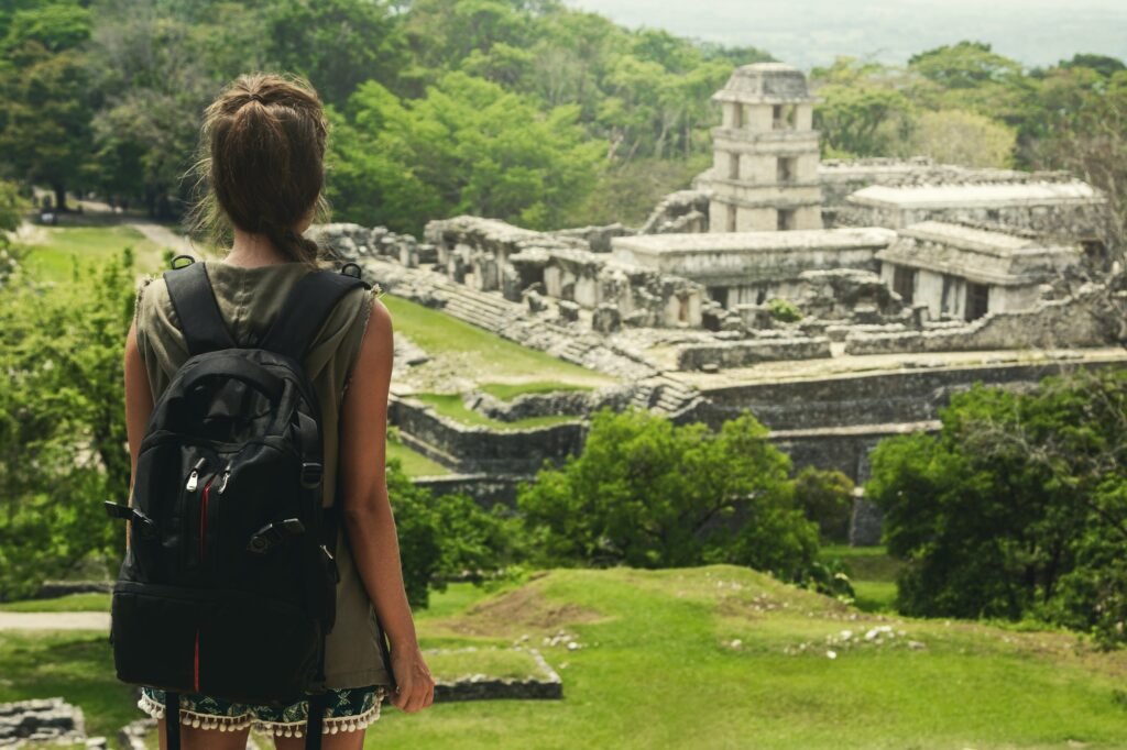 Woman with backpack beside ancient Mayan ruins